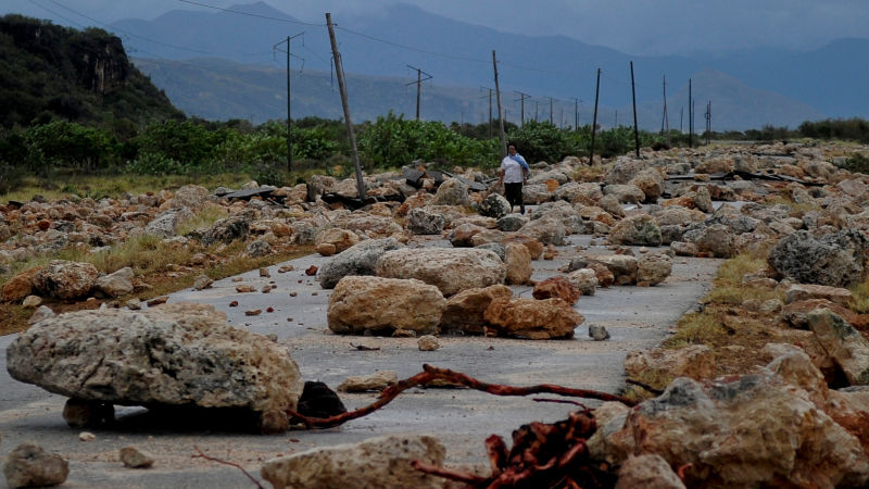 Una mujer camina a través de una carretera llena de escombros que se ubica entre Guantánamo y Baracoa. No solo el camino se llenó de rocas y más escombros, sino que la infraestructura sufrió grandes daños. La foto fue tomada el 5 de octubre. (Foto: Getty).